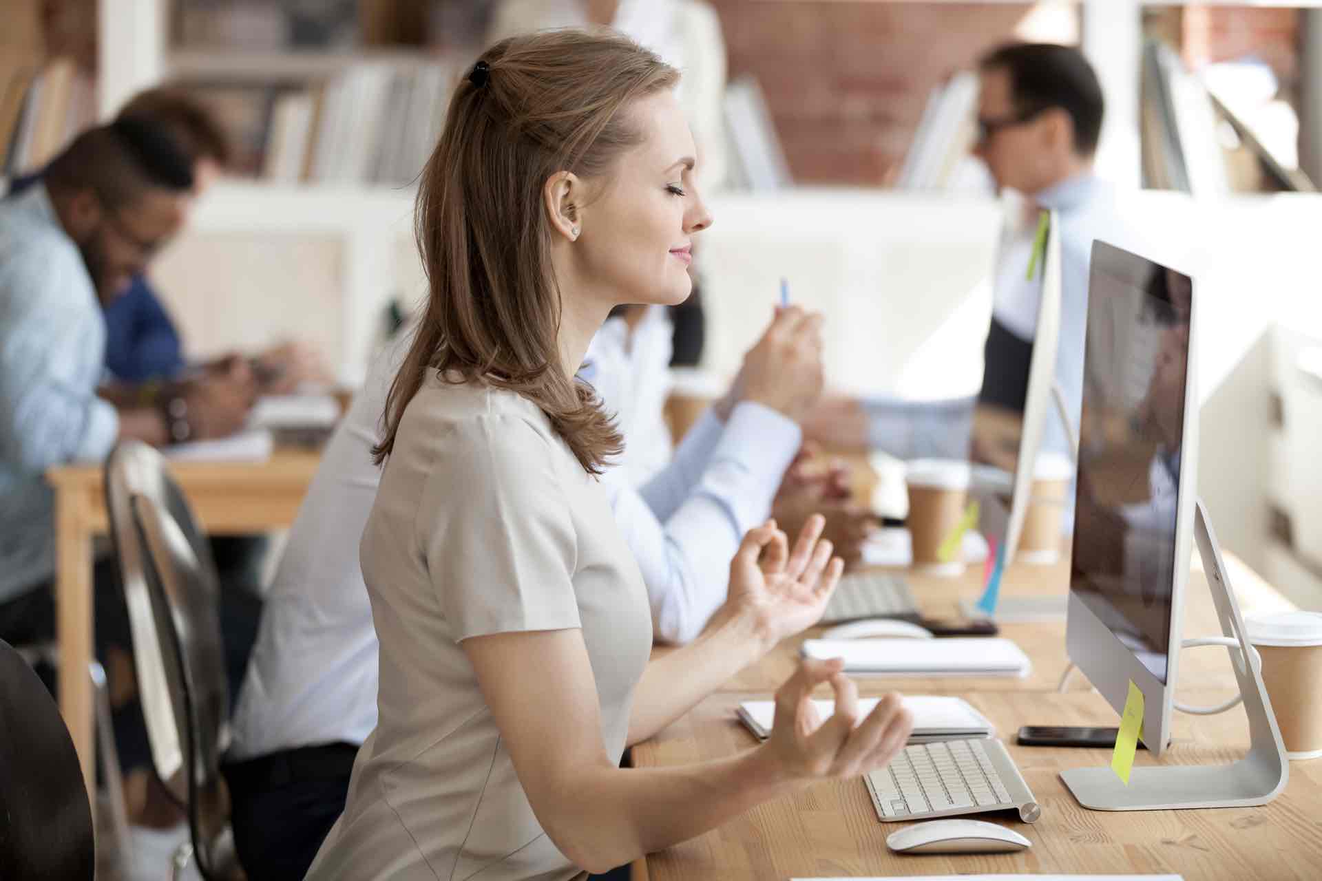 Calm,Relaxing,Businesswoman,Doing,Yoga,Exercise,,Meditating,At,Workplace,In